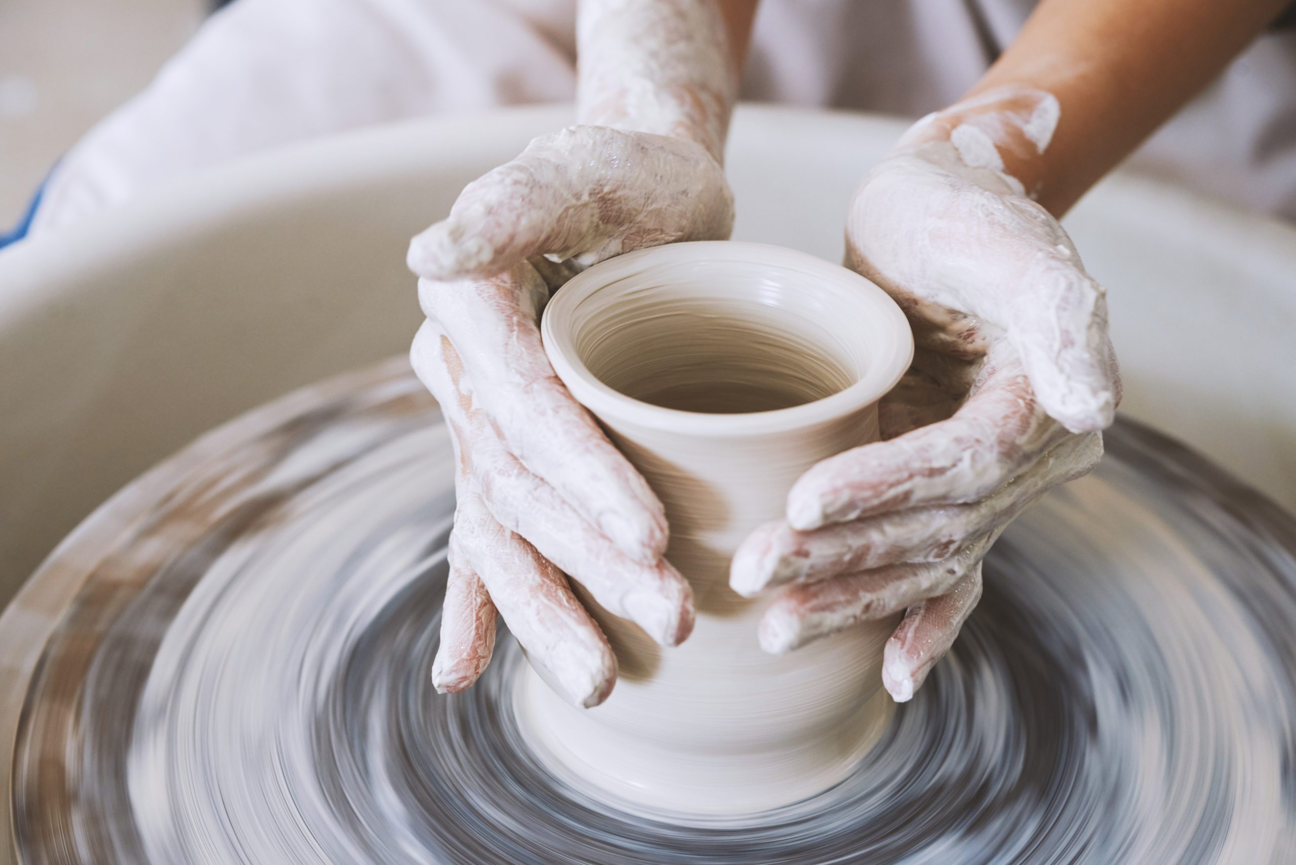 hands shaping clay on moving potter's wheel