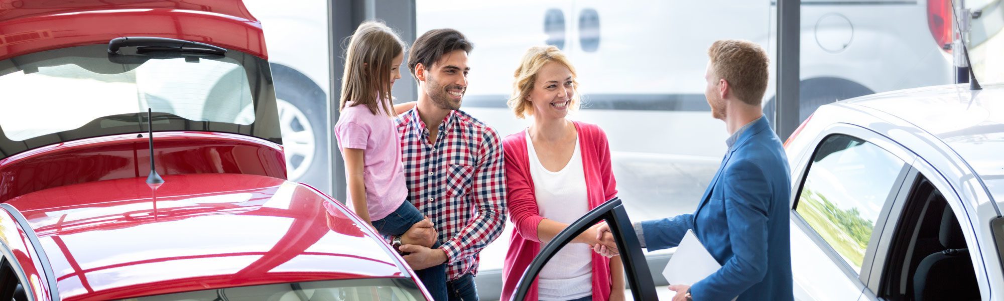 family at car dealership with salesman